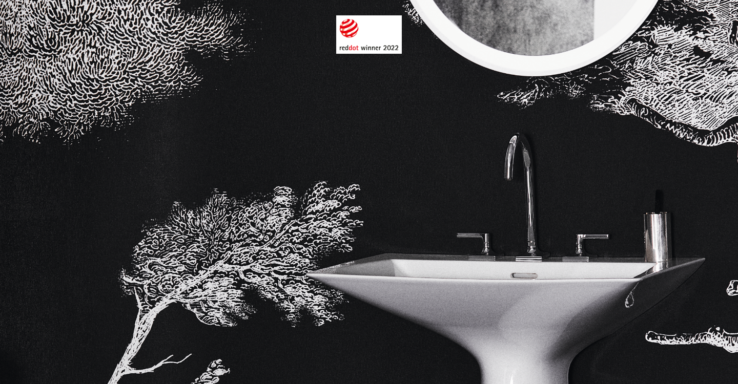 Photo du mélangeur chrome Joy Neo d'Ideal Standard installé sur le lavabo monobloc blanc Tipo-Z. En arrière-plan, tapisserie noir avec motifs blancs d'arbres et feuillages.